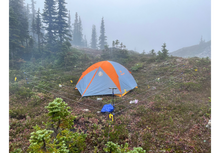 Load image into Gallery viewer, Tent set up with a bear fence in a foggy forested area in the north with trees and grass.
