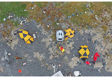 Load image into Gallery viewer, Drone view of field research camp prteted by 6 pole Bar Sentry electric  fence with guylines on rugged terrain.
